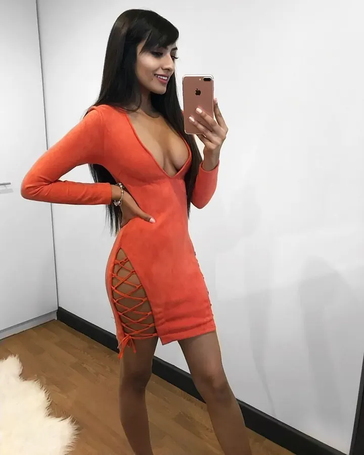 Femme aux cheveux bruns-noirs, regardant vers le côté, portant un haut orange avec découpe latérale