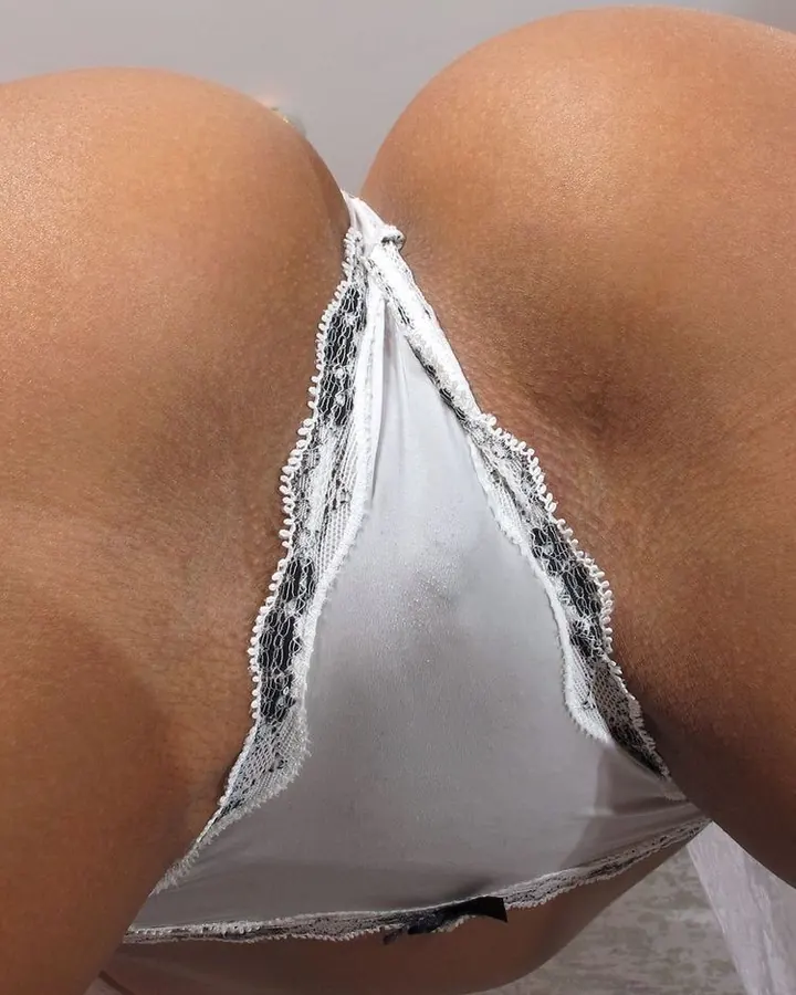 Plan rapproché du fessier d'une femme portant un string blanc en dentelle, avec un bord noir.