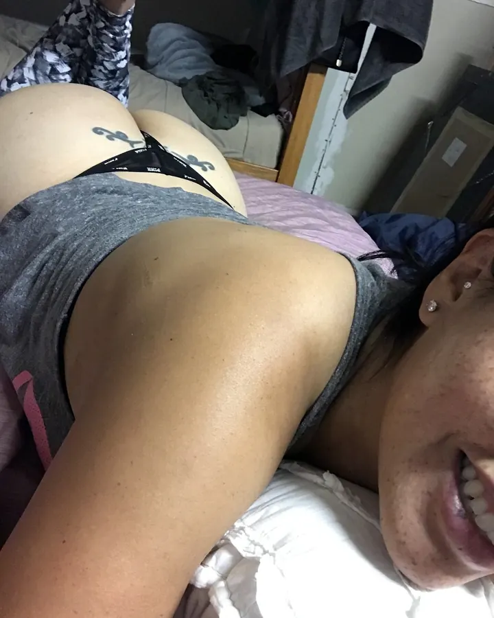 Vue arrière d'une femme en sous-vêtement rose, posant sur un lit.